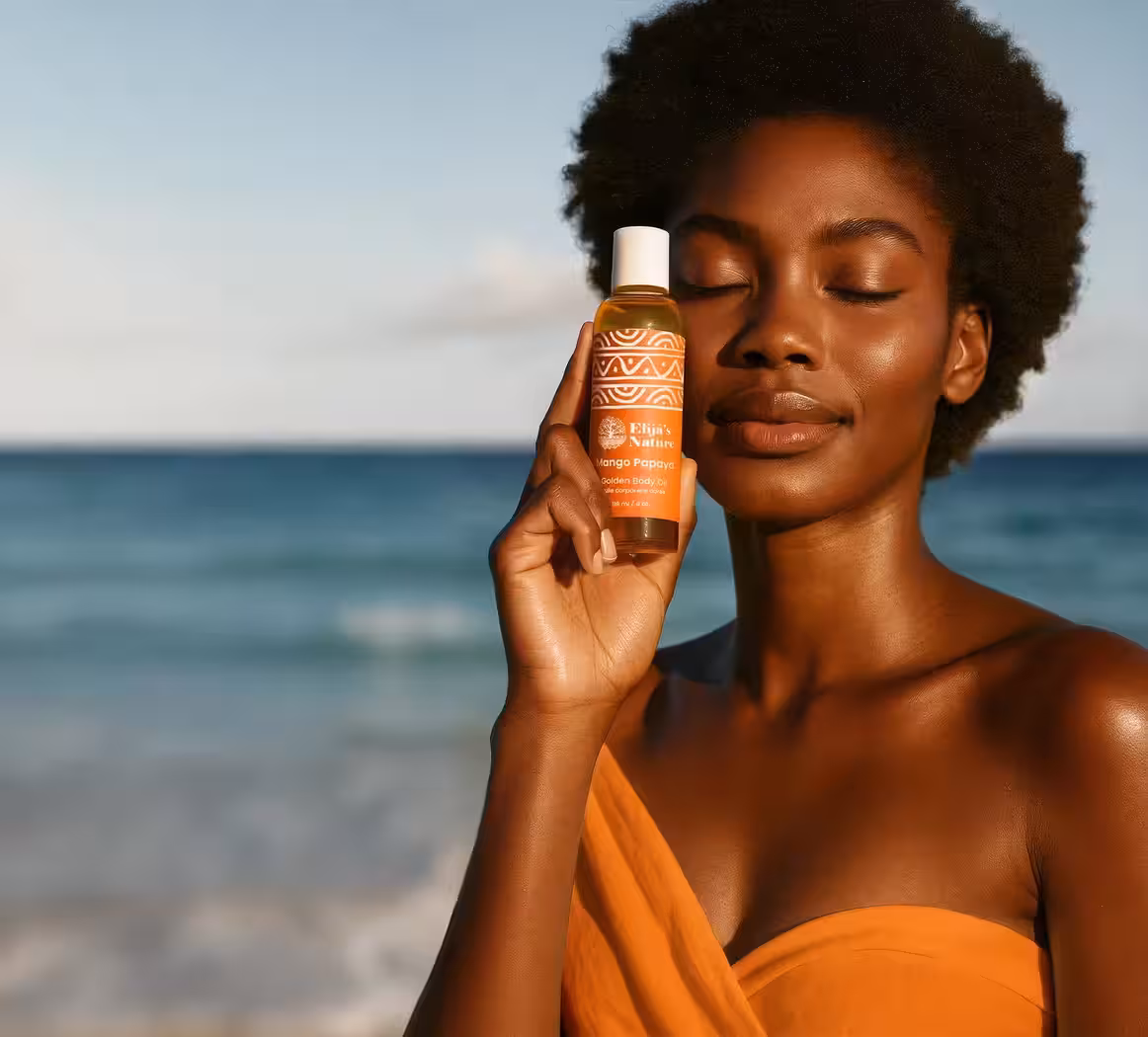 Woman holding Elija’s Nature's Mango Papaya Body Oil beside her face, smiling with closed eyes at the beach.