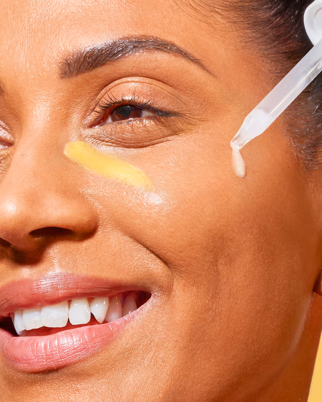 Close-up of model’s eye with Garnier SkinActive Vitamin C serum applied under eye using dropper.