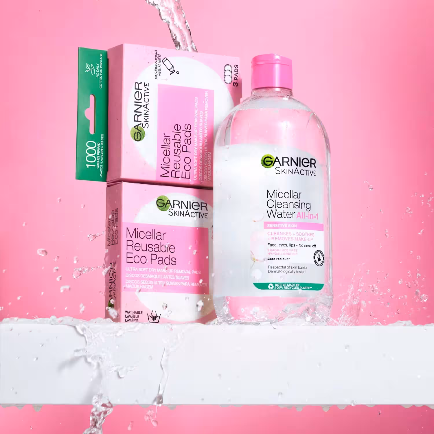 Garnier SkinActive Micellar Cleansing Water with reusable eco pads and packaging styled with water splash on pink background.