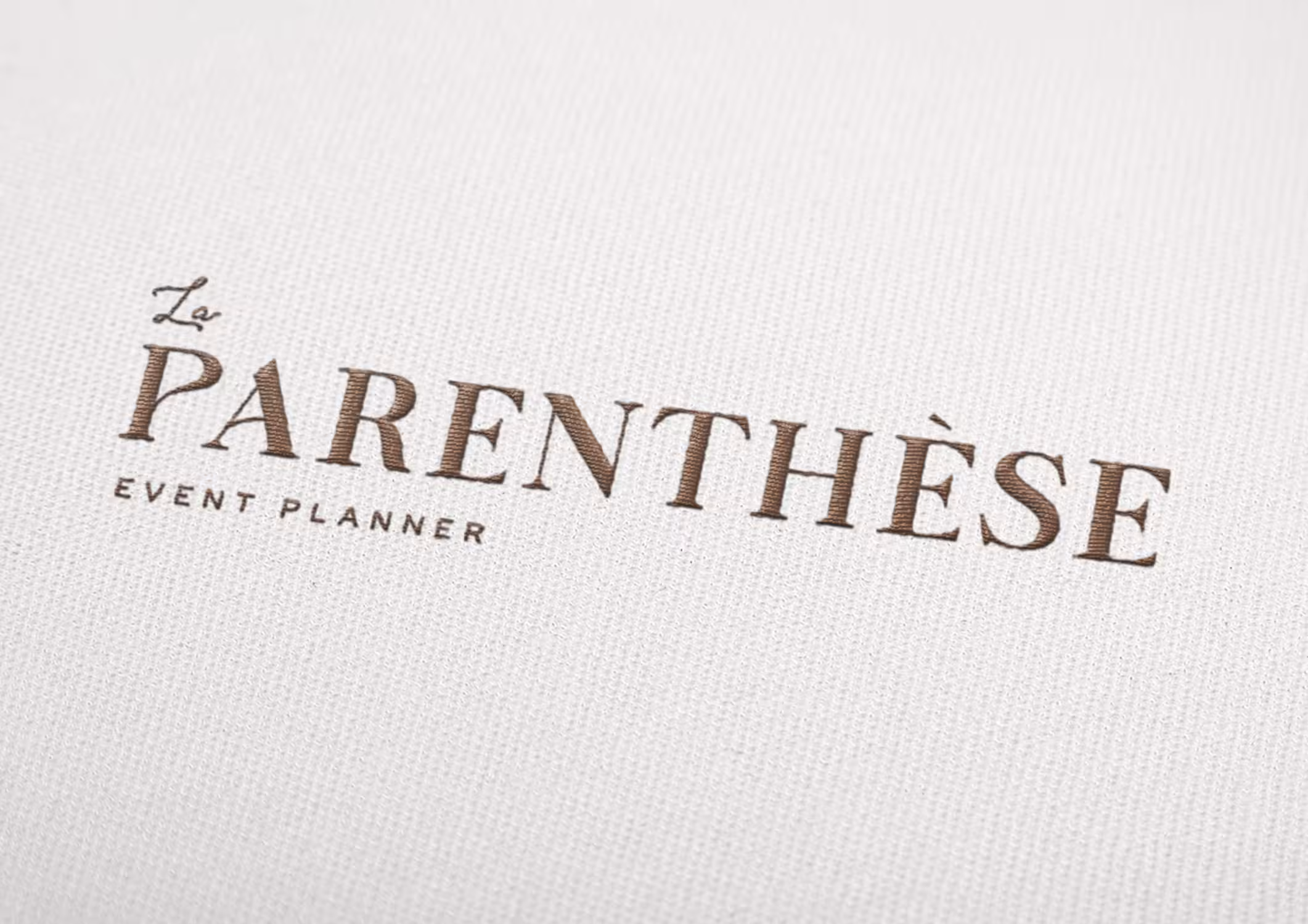 La Parenthèse embroidered logo in brown serif typography displayed on white fabric.