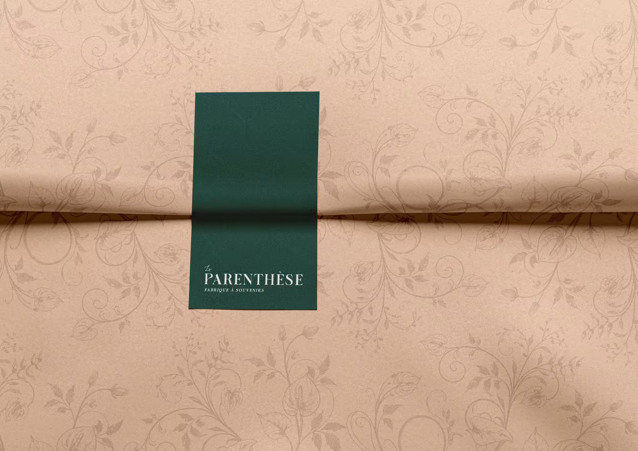 La Parenthèse champagne wrapping paper with subtle floral brand pattern and green band detail.