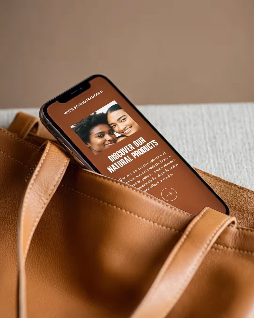 The new Studio Grade social post shown on a mobile phone screen held in a leather bag.